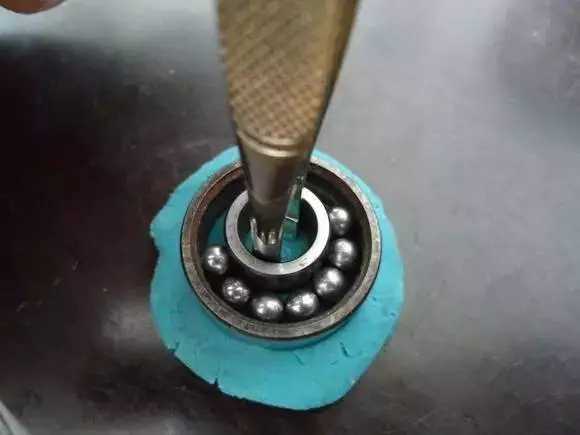 用鑷子或別的相近的物體越過(guò)內(nèi)圈，同時(shí)向滾珠的方向用力頂住